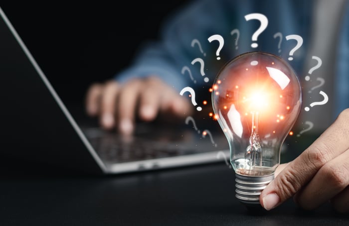 GrowthHive Do You Know How to Win - Businessman holding glowing light bulb with question icon. Find answers online. FAQ search for information on the internet